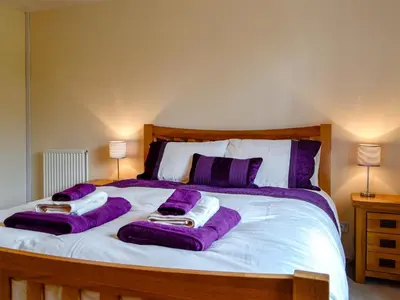 a large bed with purple blankets and pillows on it at Bryn Villa in Newbridge on Wye