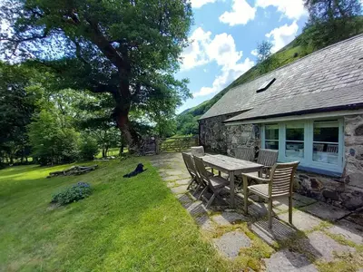 a table and chairs in front of a house at Gesail Barn and Farmhouse in Machynlleth