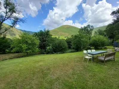 a table and chairs in a field with hills in the background at Gesail Barn and Farmhouse in Machynlleth