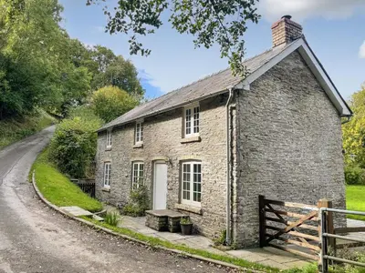 an old brick house on the side of a road at Bridge End Cottage in Cregrina