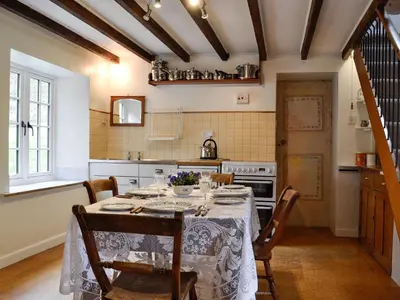a dining room with a table and a kitchen at Bridge End Cottage in Cregrina
