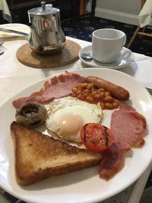 a plate of breakfast food with eggs bacon beans and toast at Helmsman Guesthouse in Aberystwyth