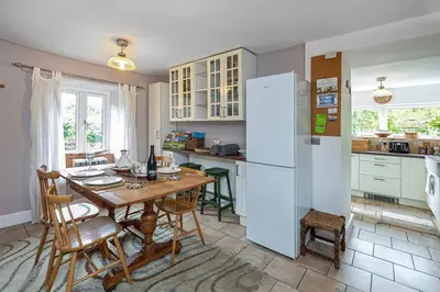a kitchen with a table and a white refrigerator at Hawddamor in Dolgellau