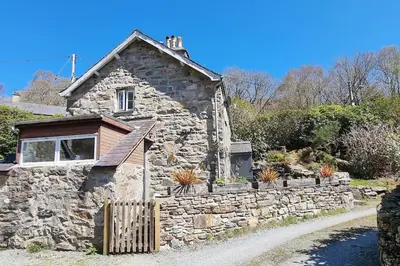 an old stone house with a fence in front of it at Hawddamor in Dolgellau