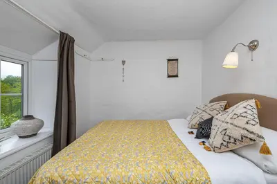 a bedroom with a bed with a yellow blanket and a window at Hawddamor in Dolgellau