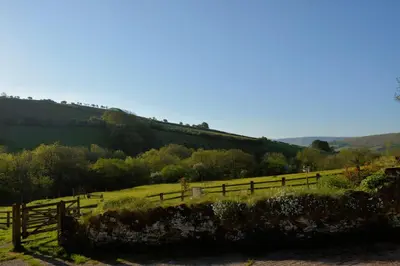 a fence in a field with a train on a hill at Snug Oak Hut with a view on a Welsh Hill Farm in Brecon