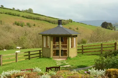a gazebo in a field next to a fence at Snug Oak Hut with a view on a Welsh Hill Farm in Brecon