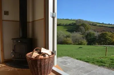 a view of a field from a porch with a fireplace at Snug Oak Hut with a view on a Welsh Hill Farm in Brecon