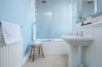 a white bathroom with a sink and a tub and a sink at LLys Aeron 