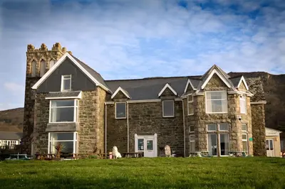 a large brick house with a grass field in front of it at Min y Mor Hotel in Barmouth