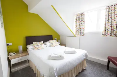 a bedroom with a bed with a green wall at Min y Mor Hotel in Barmouth