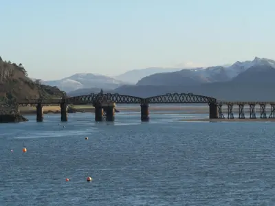 a bridge over the water with mountains in the background at Showman's Wagon at Coed Cae in Dolgellau
