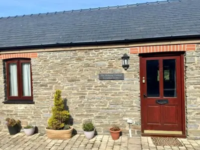 a brick building with a wooden door and potted plants at The Milking Parlour in Aberystwyth