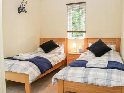a bedroom with two beds and a window at Alder River Lodge Clun Valley Luxury Hot Tub Break in Craven Arms