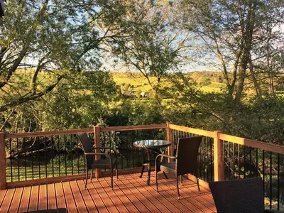 a wooden deck with chairs and a table on it at Alder River Lodge Clun Valley Luxury Hot Tub Break in Craven Arms