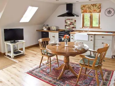 a kitchen with a wooden table and chairs in a room at Rhiastyn Barn in Hyssington