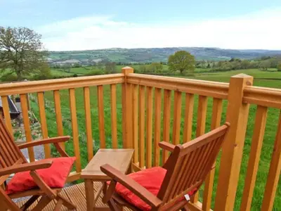 two rocking chairs sitting on a deck with a view at Rhiastyn Barn in Hyssington