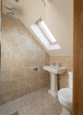 a bathroom with a toilet and a sink and a skylight at Rhiastyn Barn in Hyssington