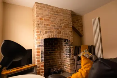 a brick fireplace in a living room with a tv at Rose Cottage in Shrewsbury