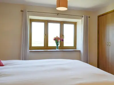 a bedroom with a bed with a vase of flowers in a window at Upper Close - Uk10873 in Evenjobb