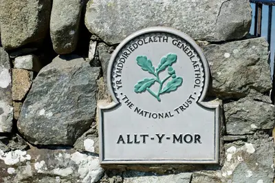 a sign on top of a pile of rocks at Allt y Mor in Harlech