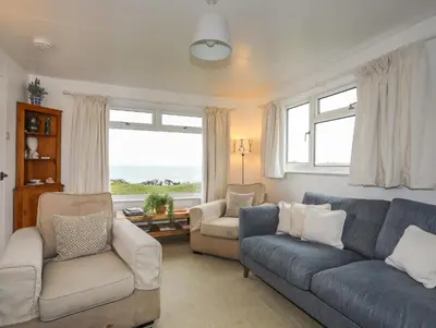 a living room with a blue couch and two chairs at Allt y Mor in Harlech
