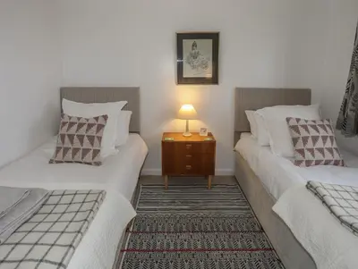 two beds in a room with a lamp on a table at Allt y Mor in Harlech