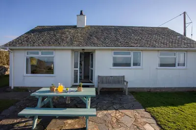 a blue picnic table in front of a house at Allt y Mor in Harlech