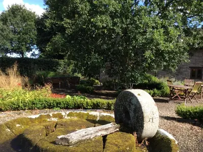 a gravestone in a garden with a pond at The Old Barn in Hereford