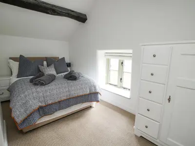 a bedroom with a bed and a white dresser at Rectory Cottage in Oswestry