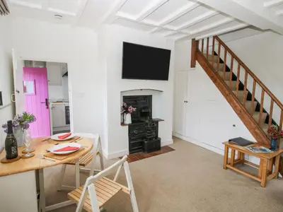 a living room with a table and a tv on the wall at Rectory Cottage in Oswestry