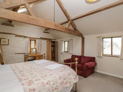 a bedroom with a bed and a red chair at The Granary in Hereford