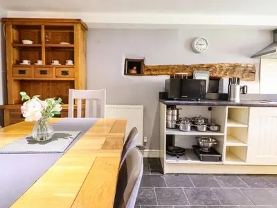a kitchen with a wooden table and a kitchen with a counter at Cwm Yr Afon Mawr in Llanbedr