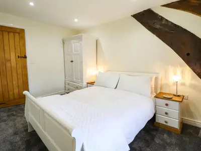 a bedroom with a large white bed and a wooden door at Cwm Yr Afon Mawr in Llanbedr