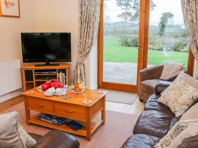 a living room with a tv and a couch and a table at Southdown in Much Wenlock