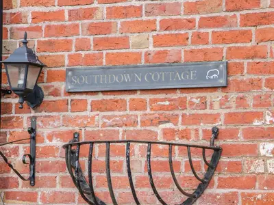 a sign on a brick wall with a street sign at Southdown in Much Wenlock