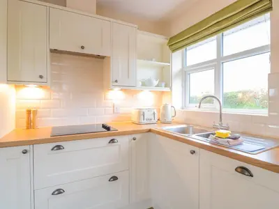 a kitchen with white cabinets and a sink and a window at Bower View in Hereford