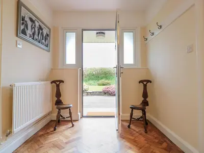 two chairs in the hallway of a home with the door open at Bower View in Hereford