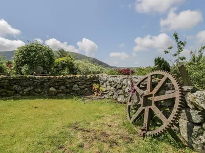 a stone wall and a stone wheel in a yard at The Stable Cottage in Llanbedr