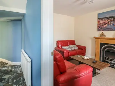 a living room with a red chair and a fireplace at Bari in Aberaeron