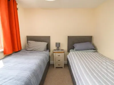 two beds in a small room with orange curtains at Bari in Aberaeron