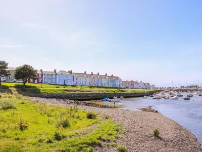 a row of houses next to a river with boats at Bari in Aberaeron