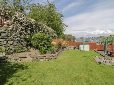 a garden with a stone wall and a fence at Clyd Fan in Harlech