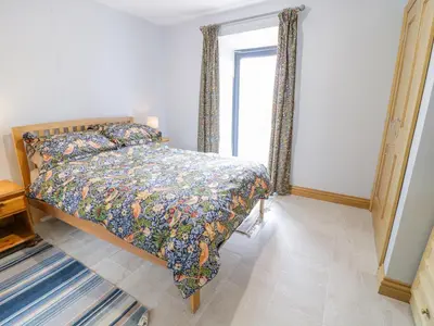 a bedroom with a bed with a comforter and a window at 7evern Porth Farm in Caersws