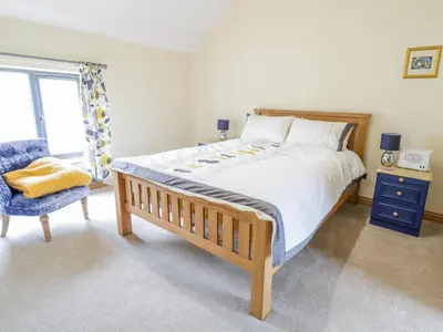a bedroom with a large bed and a blue chair at 7evern Porth Farm in Caersws