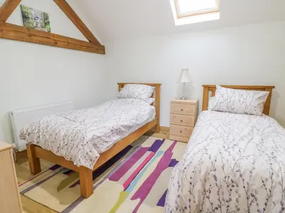 a bedroom with two twin beds and a rug at 7evern Porth Farm in Caersws