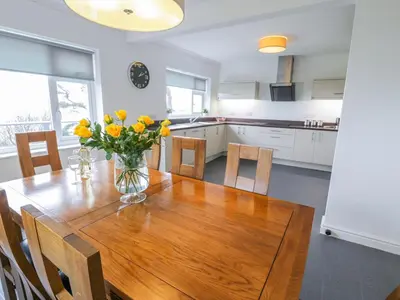 a kitchen with a wooden table with yellow flowers on it at Hendre Wylan in Barmouth