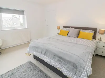 a white bedroom with a large bed with yellow pillows at Hendre Wylan in Barmouth
