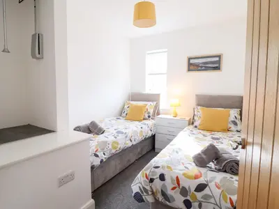 two beds in a small room with yellow pillows at Arnant in Dolgellau
