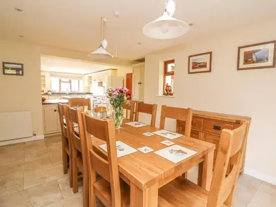 a kitchen and dining room with a wooden table and chairs at Treboeth in Knighton